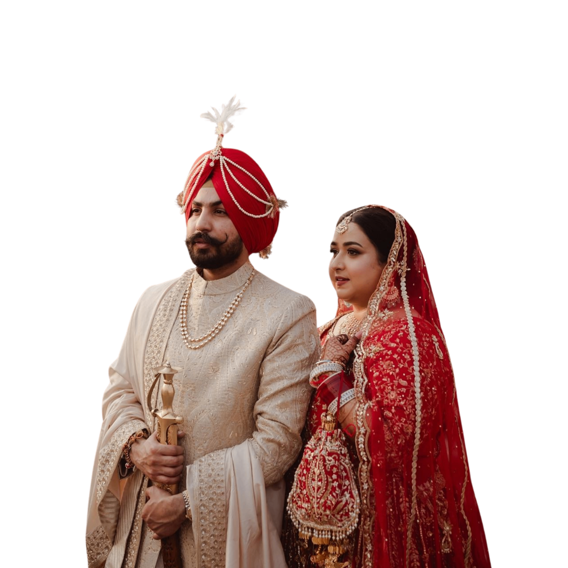 Groom in a cream sherwani standing beside a bride in a red lehenga
